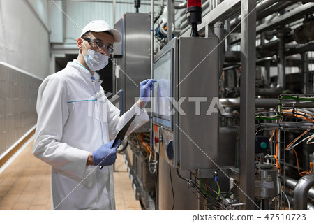 technologist taking necessary notes while standing at production department of dairy factory technologist taking necessary notes while standing at production department of dairy factory 47510723