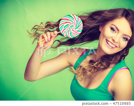 Smiling girl with lollipop candy on green 47510985