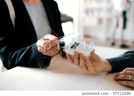 A midsection of customer and shop assistant making contactless payment in a shop. 47512096