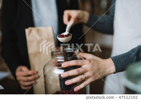 A midsection of a customer buying groceries in a zero waste shop. A close-up. 47512102