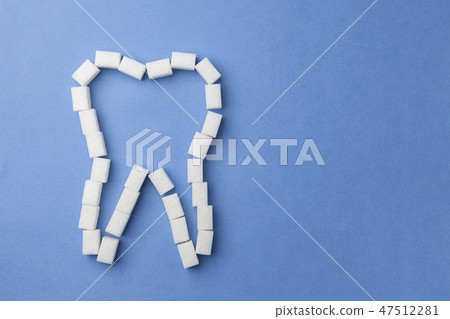 white tooth made of sugar on a blue background. The concept of oral health. 47512281