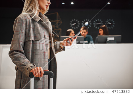 Close-up of a smiling successful businesswoman pulling suitcase 47513883