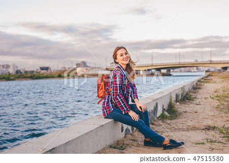 Smiling woman sitting on the riverbank 47515580
