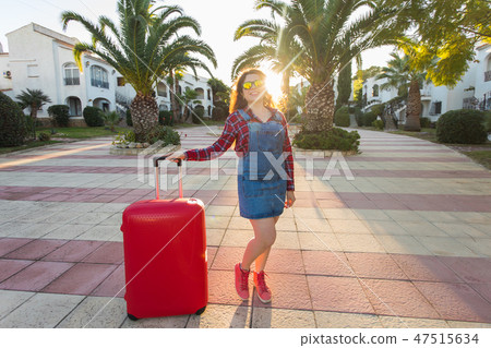 Journey, holidays and summer concept - young woman with red travel suitcase arrived in hotel 47515634