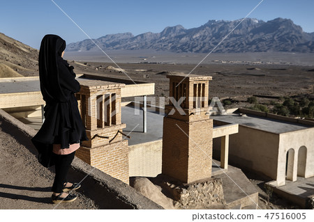 One girl in black chador looks at mountains, Yazd 47516005