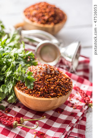 Dried and crushed chili peppers in wooden bowles. 47516053