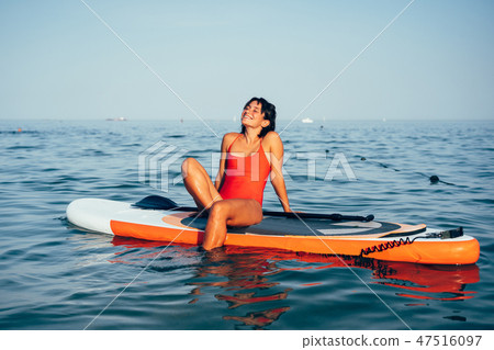 Young woman doing yoga on sup board with paddle 47516097