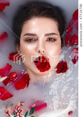 Beautiful girl with classic make-up and red lips in the bathroom with flowers. Beauty face. Beautiful girl with classic make-up and red lips in the bathroom with flowers. Beauty face. 47516786