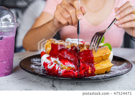 woman eating strawberry waffles with knives and forks 47524471