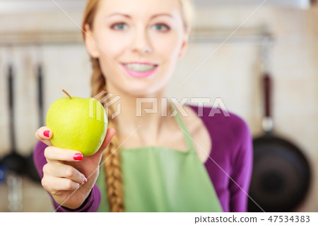 Woman young housewife in kitchen with apple fruit Woman young housewife in kitchen with apple fruit 47534383
