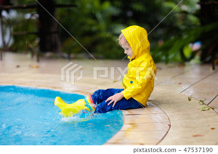Kid in swimming pool in rain. Tropical storm. Kid in swimming pool in rain. Tropical storm. 47537190