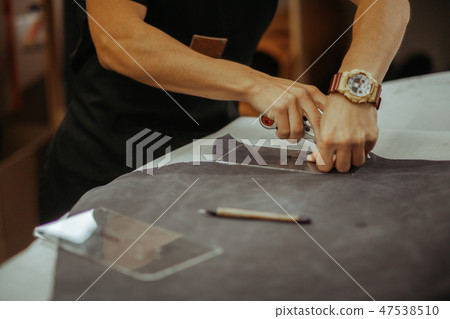 Close up of a master working with leather textile at his workshop using tools. Handmade concept. 47538510
