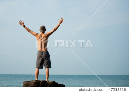 A man raising his hands in the sea 47538836