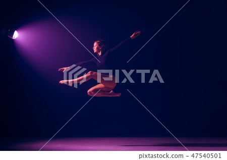 Young female ballet dancer on neon lights studio background. 47540501