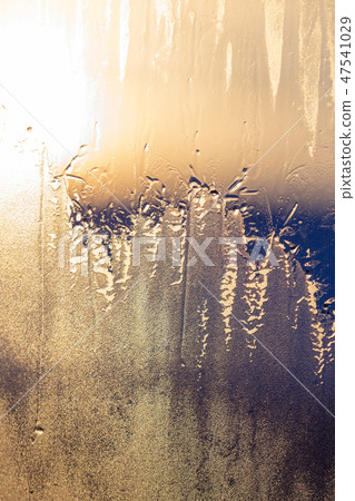 Sunset the sun shines through the frozen window 47541029