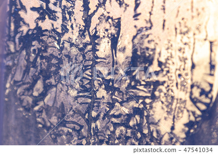 The sunset sun shines through the frozen window. Ice patterns on glass 47541034