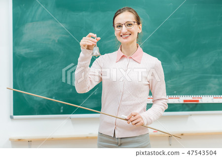 Teacher ringing the bell for class to begin 47543504