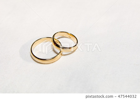 Two golden wedding rings on the white fabric. Two golden wedding rings on the white fabric. 47544032