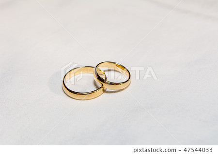 Two golden wedding rings on the white fabric. Two golden wedding rings on the white fabric. 47544033