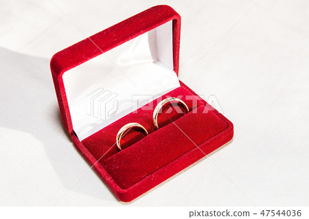 Two golden wedding rings on the white fabric.  47544036