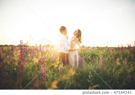Emotional beautiful bride hugging newlywed groom from behind sunset at a field closeup Emotional beautiful bride hugging newlywed groom from behind sunset at a field closeup 47544141