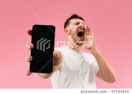 Young handsome man showing smartphone screen isolated on pink background in shock with a surprise 47544854