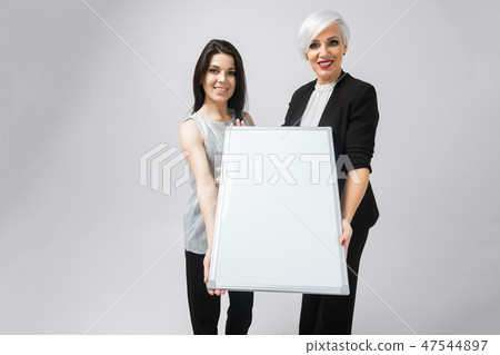 two girls holding an empty poster isolated on white background two girls holding an empty poster isolated on white background 47544897