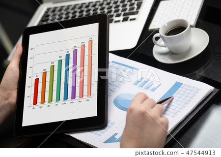 Close-up of hand holding tablet and point pen at chart 47544913