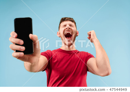 Young handsome man showing smartphone screen isolated on blue background in shock with a surprise 47544949
