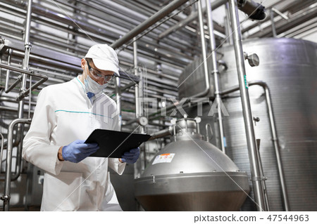 technologist taking necessary notes while standing at production department of dairy factory 47544963