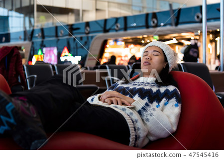 Girl taking a nap while waiting at the airport Girl taking a nap while waiting at the airport 47545416