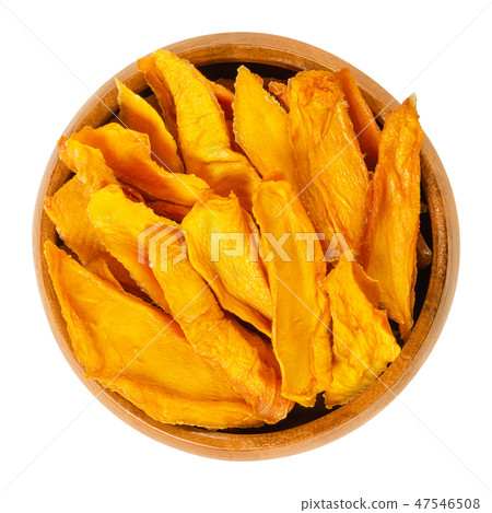 Dried mango strips in wooden bowl over white Dried mango strips in wooden bowl over white 47546508