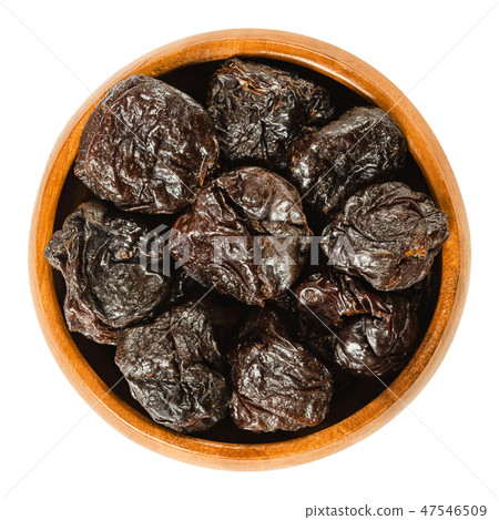 Prunes, dried plums in wooden bowl over white Prunes, dried plums in wooden bowl over white 47546509