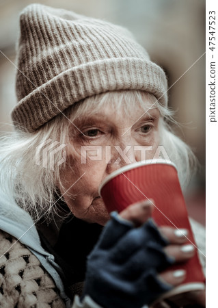 Portrait of a poor aged woman drinking hot tea 47547523