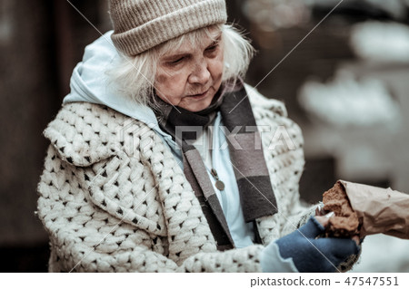 Sad aged woman taking a piece of bread Sad aged woman taking a piece of bread 47547551