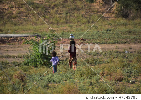 A girl carrying his child's water bottle on his head while living in the desert during the Pushkar camel festival in Rajasthan Province, India 47549785