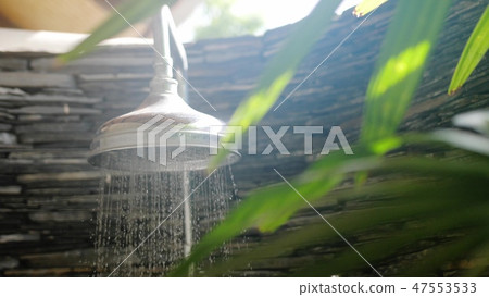 Summer shower head water spray in beautiful bathroom with tropical plants on sunny day 47553533