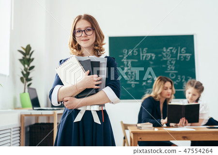 Portrait of smiling school girl with books in classroom Portrait of smiling school girl with books in classroom 47554264