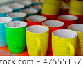 Many colored mugs in the store 47555137
