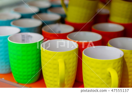Many colored mugs in the store 47555137