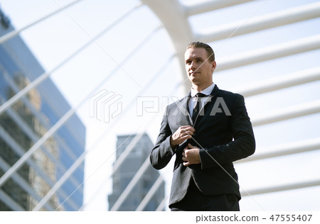 Business man buttoning his suit standing in city Business man buttoning his suit standing in city 47555407