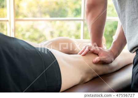 Male therapist giving leg massage to patient 47556727