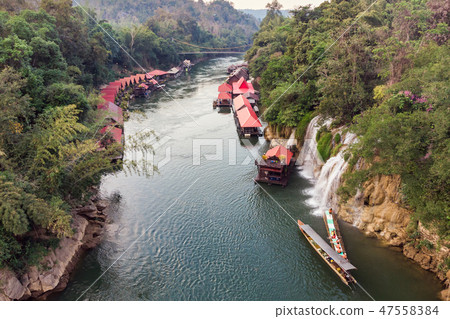 Wooden boat sailing river kwai with waterfall 47558384