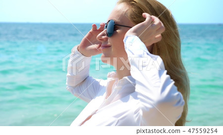 Business woman in sunglasses on the beach. she rejoices in the sea and the sun. she unbuttoned her Business woman in sunglasses on the beach. she rejoices in the sea and the sun. she unbuttoned her 47559254