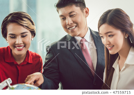Businesspeople looking at globe Businesspeople looking at globe 47559715