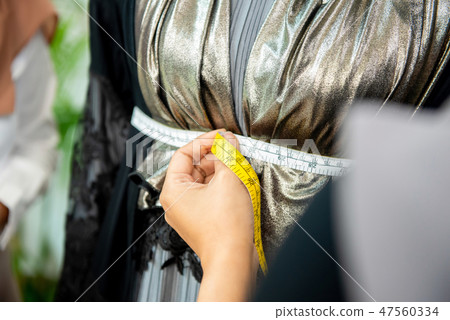 Female designer hand using a measuring tape 47560334