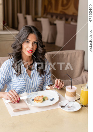 Beautiful young woman enjoying coffee cappuccino or latte in a glass cup with foam. Light breakfast Beautiful young woman enjoying coffee cappuccino or latte in a glass cup with foam. Light breakfast 47560469