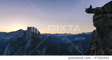 Man on a cliff with view of rock mountain below Man on a cliff with view of rock mountain below 47562093