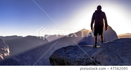 Man on a cliff and majestic mountains in Yosemite Man on a cliff and majestic mountains in Yosemite 47562095