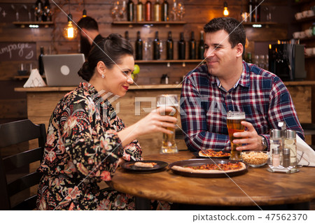 Couple relaxing at pub and eating pizza. Couple relaxing at pub and eating pizza. 47562370